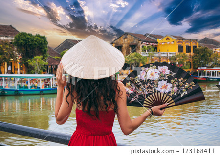 back of woman tourist traveler in Vietnamese hat with a fan on a bridge in Hoi An in Vietnam in Asia 123168411