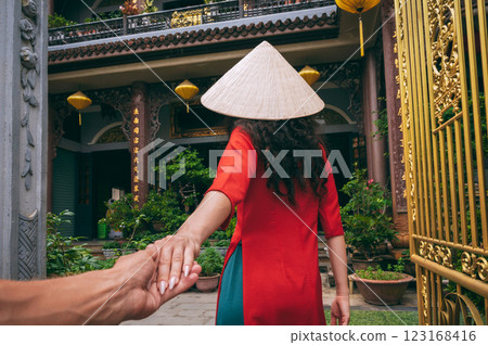 Follow me with back of a female traveler tourist in Vietnamese hat at a temple in Vietnam in Asia. The concept of travel in Asia 123168416