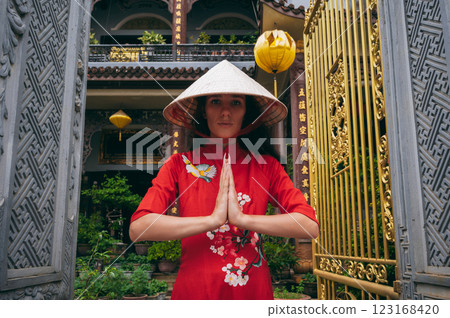 woman traveler tourist in a Vietnamese hat prays at Buddhist temple on pagoda in Hoi An in Vietnam in Asia 123168420
