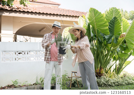 Diverse couple sharing gardening moments, showcasing a potted plant in a bright backyard. 123168513