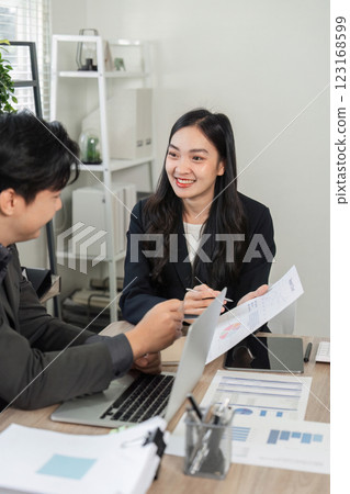 Diverse business colleagues discussing charts and data analysis in a contemporary office setting. 123168599