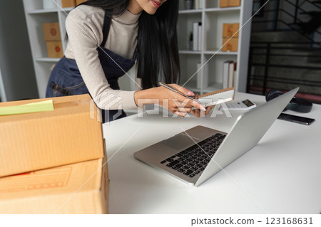 Entrepreneur organizing packages and taking notes in a contemporary office space. Entrepreneur organizing packages and taking notes in a contemporary office space. 123168631