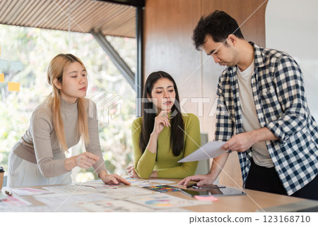 Diverse team analyzing design materials and discussing concepts in an office. 123168710