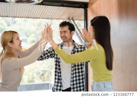 Diverse colleagues celebrating teamwork and success in a modern office environment. 123168777