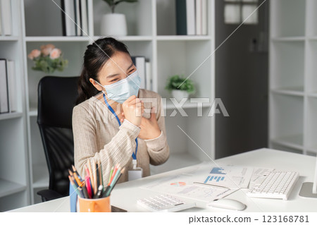 Woman in a mask smiling while working at her office desk. Woman in a mask smiling while working at her office desk. 123168781
