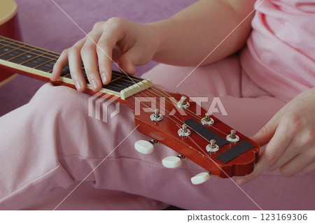 Woman's hands tuning guitar. Hand moves methodically tightening and loosening strings before playing Woman's hands tuning guitar. Hand moves methodically tightening and loosening strings before playing 123169306