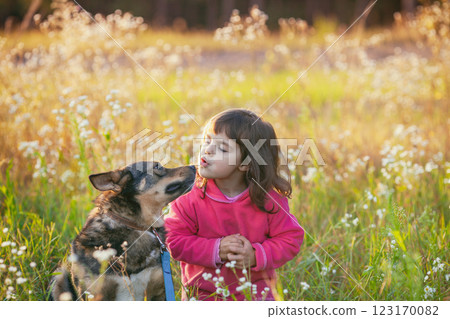Happy Little girl with a dog walking in the flower field in spring 123170082
