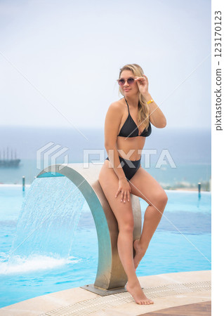 Portrait of beautiful woman in swimwear relaxing in swimming pool in resort 123170123
