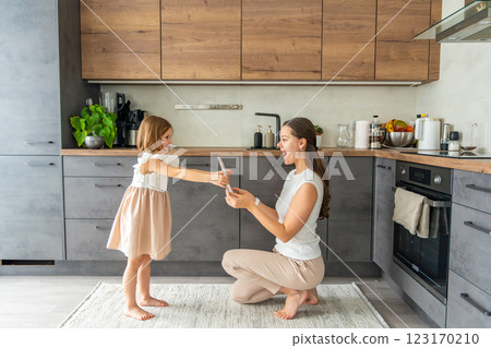 Little girl giving bouquet of flowers and drawing to her mum on the home kitchen. Mothers day, birthday or International Women's Day 8 march concept 123170210
