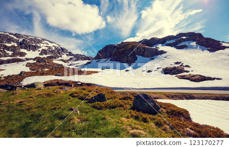 The mountain range is covered with melting snow. Nature park on road 520 from Roldal to Sauda in summer. Beautiful nature of Norway The mountain range is covered with melting snow. Nature park on road 520 from Roldal to Sauda in summer. Beautiful nature of Norway 123170277