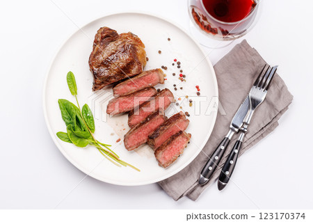 A perfectly cooked sliced striploin steak with a juicy, tender texture, served alongside a glass of rich red wine 123170374