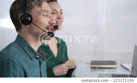 Focused male call center operator in green casual shirt is assisting clients online, providing customer support and answering inquiries. Call center concept Focused male call center operator in green casual shirt is assisting clients online, providing customer support and answering inquiries. Call center concept 123171116