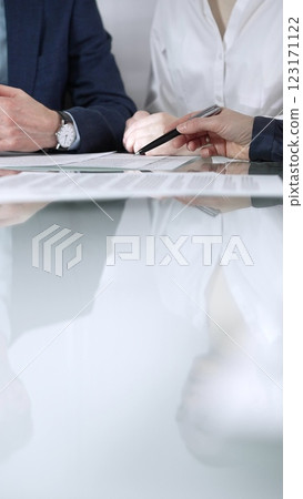 Unrecognizable business people are reviewing contract terms during a meeting while sitting at the glass table in office, vertical close up view. Copy space area 123171122