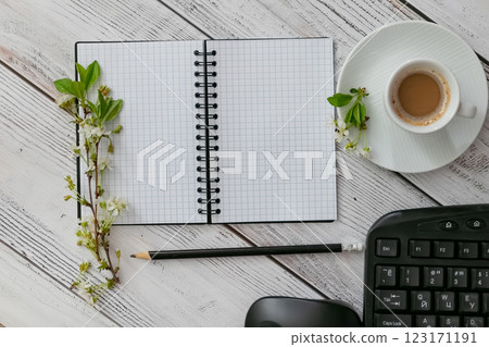 Workspace setup with coffee cup, notebook, pencil, and keyboard on wooden table 123171191