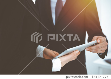 Businessman and woman using tablet computer for discussing questions in sunny office. Partners or colleagues at meeting. Cooperation concept Businessman and woman using tablet computer for discussing questions in sunny office. Partners or colleagues at meeting. Cooperation concept 123171273