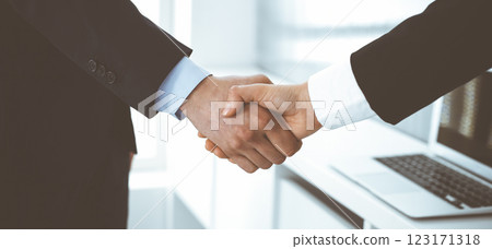 Businessman and woman shaking hands in office. Concept of handshake as success symbol in business 123171318