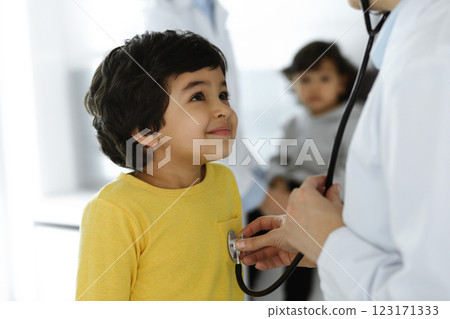 Woman-doctor examining a child patient by stethoscope. Cute arab boy at physician appointment. Medicine help concept Woman-doctor examining a child patient by stethoscope. Cute arab boy at physician appointment. Medicine help concept 123171333