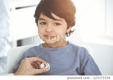 Doctor-woman examining a child patient by stethoscope in sunny clinik. Medicine concept 123171530