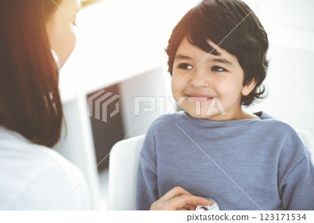 Doctor-woman examining a child patient by stethoscope in sunny clinik. Medicine concept 123171534