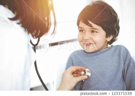 Doctor-woman examining a child patient by stethoscope in sunny clinik. Medicine concept 123171539