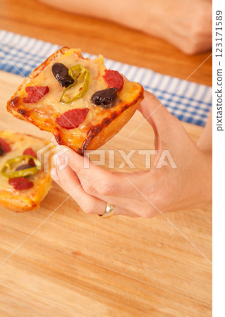 Caucasian white person holding pizza pieces on bamboo cutting board on blue napkin 123171589