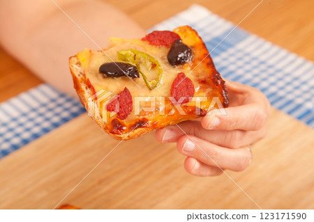 Caucasian white person holding pizza pieces on bamboo cutting board on blue napkin Caucasian white person holding pizza pieces on bamboo cutting board on blue napkin 123171590