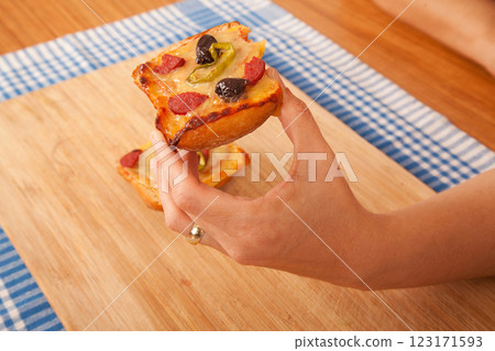 Caucasian white person holding pizza pieces on bamboo cutting board on blue napkin Caucasian white person holding pizza pieces on bamboo cutting board on blue napkin 123171593