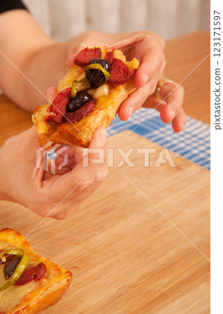 Caucasian white person holding pizza pieces on bamboo cutting board on blue napkin Caucasian white person holding pizza pieces on bamboo cutting board on blue napkin 123171597