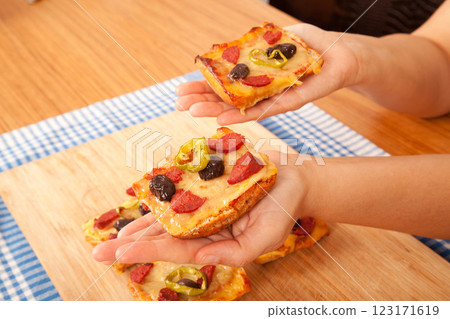 Caucasian white person holding pizza pieces on bamboo cutting board on blue napkin 123171619