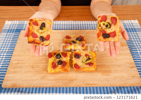 Caucasian white person holding pizza pieces on bamboo cutting board on blue napkin 123171621