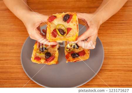 Caucasian white person holding delicious pizza slices in grey plate on wooden table Caucasian white person holding delicious pizza slices in grey plate on wooden table 123171627