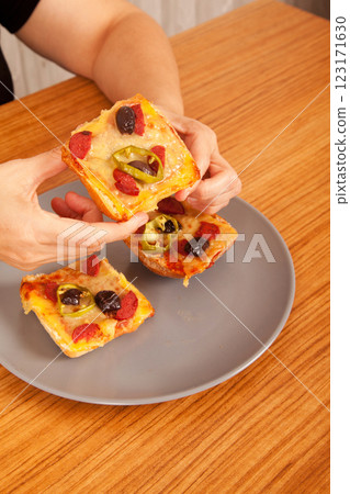 Caucasian white person holding delicious pizza slices in grey plate on wooden table Caucasian white person holding delicious pizza slices in grey plate on wooden table 123171630