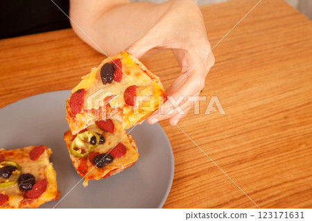 Caucasian white person holding delicious pizza slices in grey plate on wooden table Caucasian white person holding delicious pizza slices in grey plate on wooden table 123171631