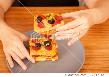 Caucasian white person holding delicious pizza slices in grey plate on wooden table Caucasian white person holding delicious pizza slices in grey plate on wooden table 123171640