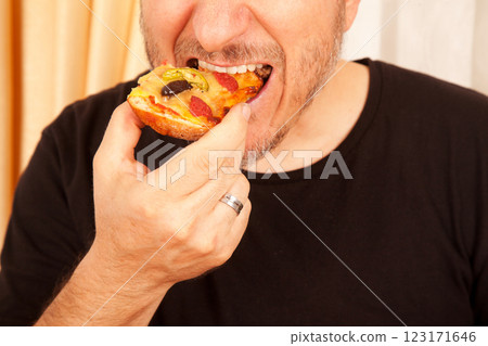 Bearded Caucasian white mature male in black t-shirt eating delicious pizza slices Bearded Caucasian white mature male in black t-shirt eating delicious pizza slices 123171646