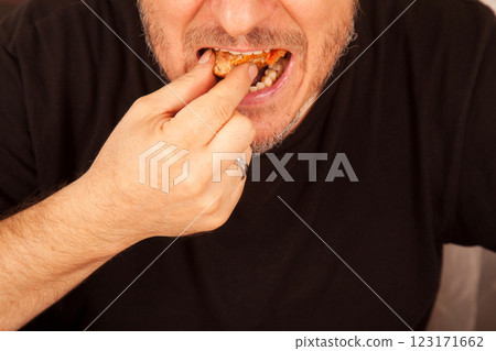 Bearded Caucasian white mature male in black t-shirt eating delicious pizza slices Bearded Caucasian white mature male in black t-shirt eating delicious pizza slices 123171662