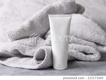 White blank squeeze cream tube near light grey bath towel top view, cosmetic mockup 123171685
