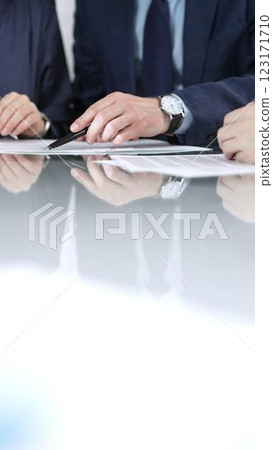 Business people are discussing a contract during meeting while sitting at the glass table in office, vertical close up view. Concept of success and team work 123171710
