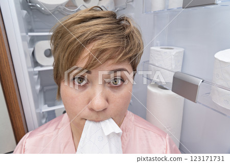 Pregnant woman eats toilet paper standing front of fully stocked shelf. Non-food items eating concept Pregnant woman eats toilet paper standing front of fully stocked shelf. Non-food items eating concept 123171731