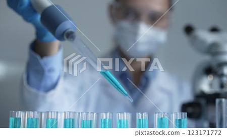 Close up of a female scientist researcher hand using a micropipette to fill up test tubes with a blue liquid in laboratory. Medicine and science 123171772