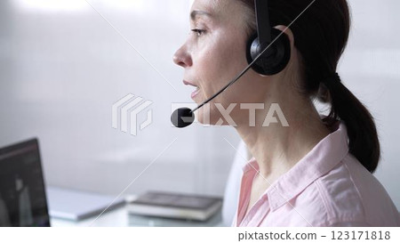 Focused female call center operator in pink casual blouse is assisting clients online, providing customer support and answering inquiries. Business call center Focused female call center operator in pink casual blouse is assisting clients online, providing customer support and answering inquiries. Business call center 123171818