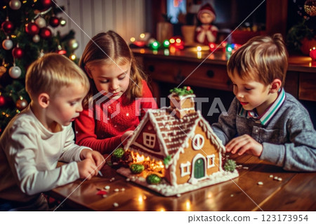 Children sit at the table and decorate a gingerbread house 123173954