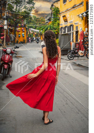 back of a young beautiful female tourist traveler in a red dress on the street in old town in Hoi An in Vietnam in Asia back of a young beautiful female tourist traveler in a red dress on the street in old town in Hoi An in Vietnam in Asia 123173993