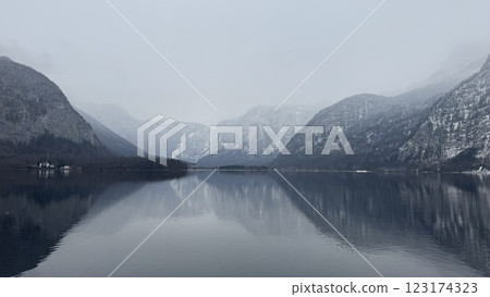 Serene Misty Mountain Lake Reflection Surrounded by Winter Snow-Covered Alpine Peaks in Hallstatt, Austria Serene Misty Mountain Lake Reflection Surrounded by Winter Snow-Covered Alpine Peaks in Hallstatt, Austria 123174323
