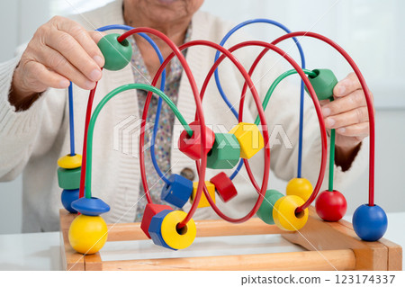 Asian elderly woman playing enhancing skill board game. Asian elderly woman playing enhancing skill board game. 123174337
