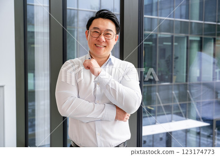 Confident Korean Businessman Smiling in Bright Modern Office Environment Confident Korean Businessman Smiling in Bright Modern Office Environment 123174773