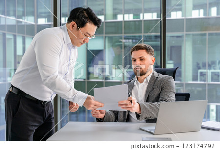 Two Businessmen Reviewing Documents in a Modern Office Environment 123174792