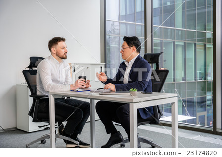 Businessmen Discussing Ideas at an Office Table in a Bright Modern Building Businessmen Discussing Ideas at an Office Table in a Bright Modern Building 123174820
