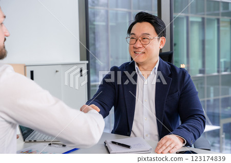 Professional Businessman Shaking Hands During a Successful Office Meeting Professional Businessman Shaking Hands During a Successful Office Meeting 123174839