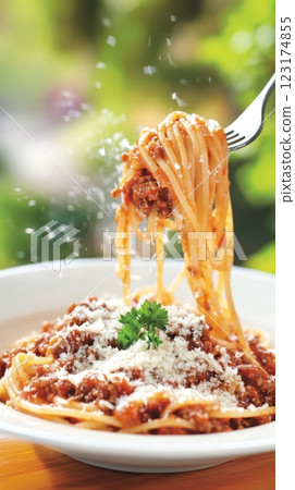 A fork lifts spaghetti Bolognese mid-air, with glistening sauce and falling Parmesan. Warm natural light and a sunlit window create a fresh, inviting Italian home-cooked atmosphere. 123174855